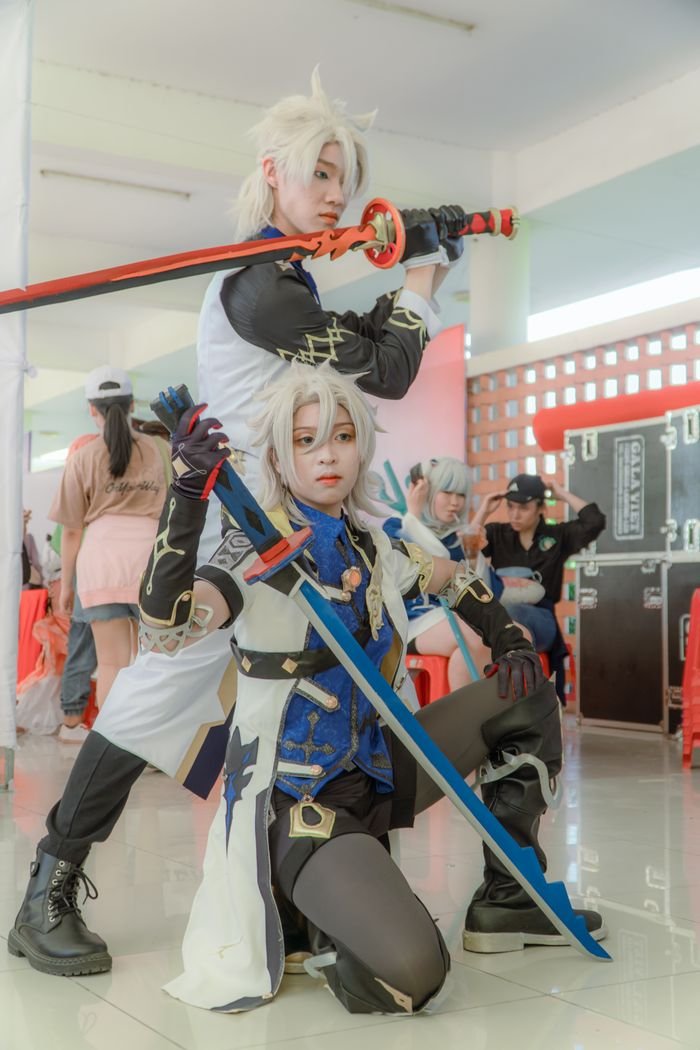 Dynamic shot of cosplayers with swords in an indoor event setting.